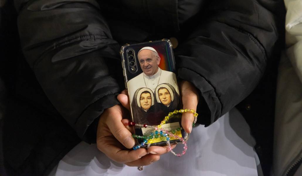 Una monja sostiene un rosario y su teléfono en la plaza de San Pedro. Dentro de su funda, tiene una foto del Papa Francisco