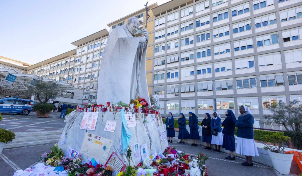 Religiosas rezando por la salud del Papa Francisco frente a la estatua de Juan Pablo II ante la fachada del hospital Gemelli de Roma