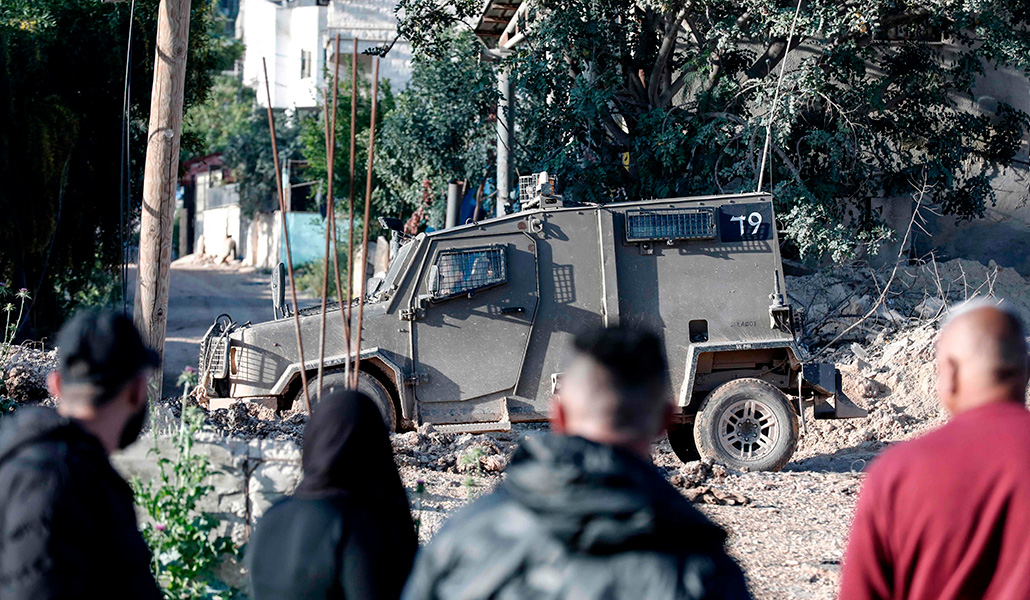 Militares israelíes patrullan en un cementerio del campo de refugiados de Yenín (Cisjordania) mientras los palestinos visitan a sus difuntos ante el final del Ramadán