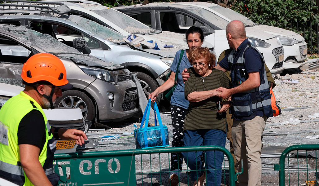 Las fuerzas de seguridad custodian a ciudadanos de Tel Aviv tras la caída de misiles del jueves entre coches dañados.