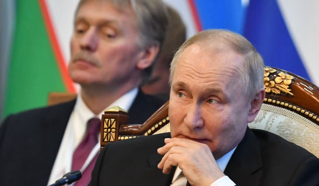 Putin con su portavoz, Peskov, detrás.