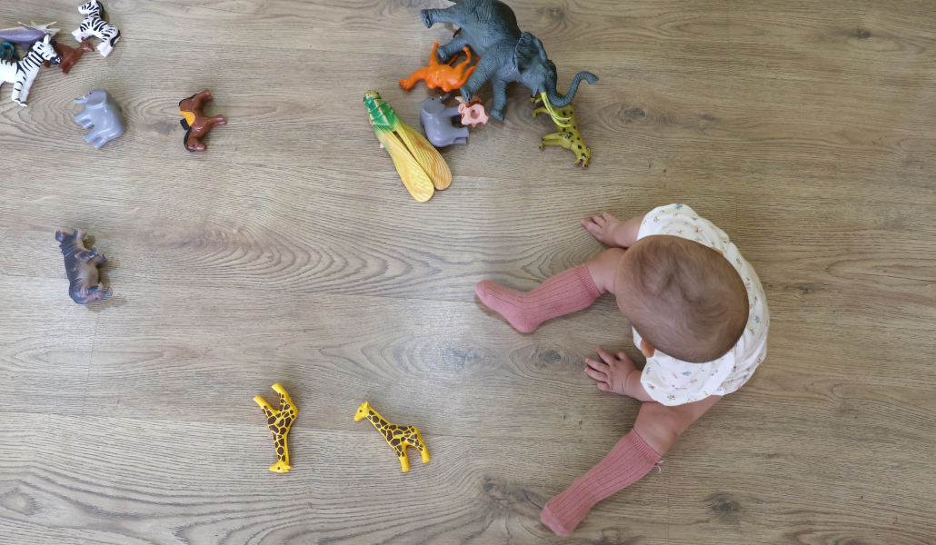 Foto de recurso de un bebe sentado jugando en el suelo