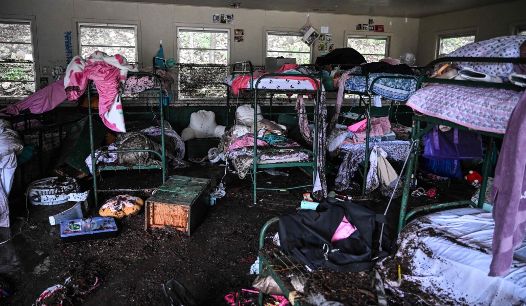Interior de una de las cabañas de Camp Mystic, con camas y pertenencias de las niñas desplazadas y llenas de barro negro.
