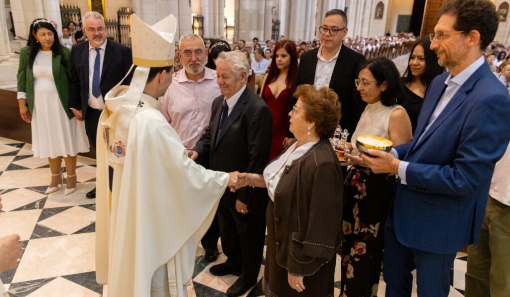 El cardenal recibe las ofrendas de manos de una familia