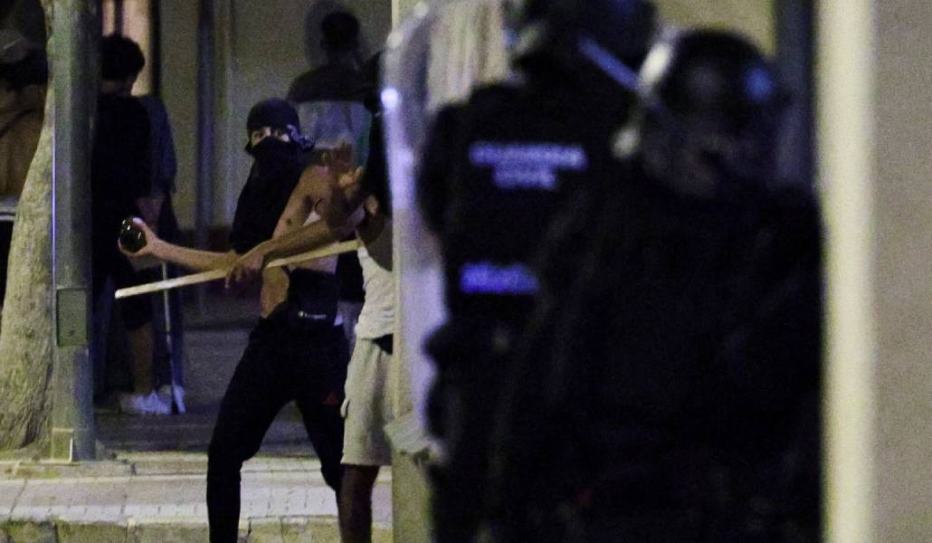 Algunos participantes en la violencia lanzan piedras contra la Policía.