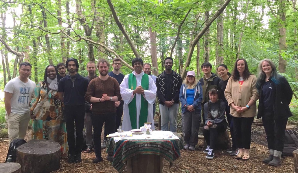 Un grupo de jóvenes y un sacerdote celebra Misa en medio de un bosque.