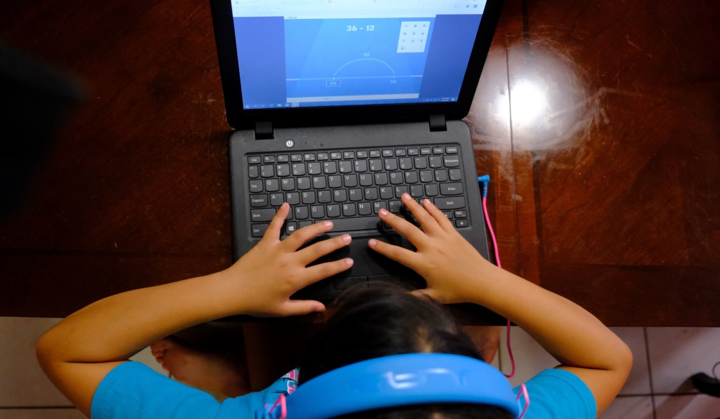 Un niño con cascos mira la pantalla de un ordenador.