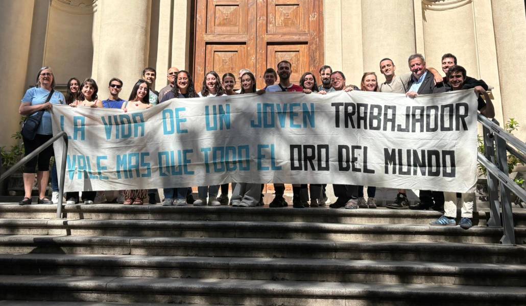 Los asistentes a la celebración con una pancarta por el trabajo digno.