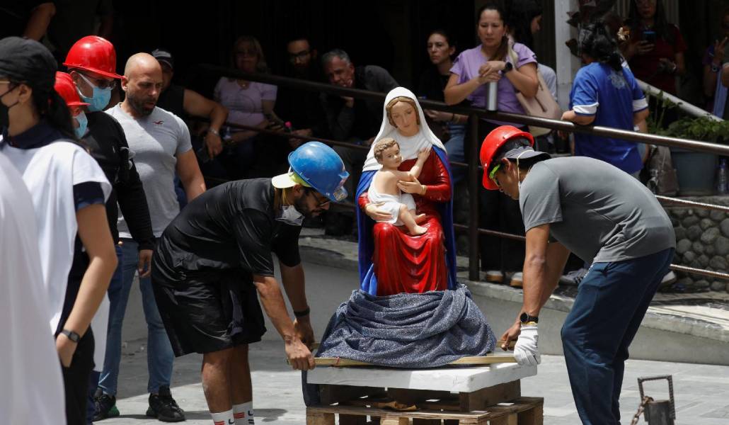 Voluntarios colocan en la calle la imagen de una Virgen y el Niño rescatada de un edificio.