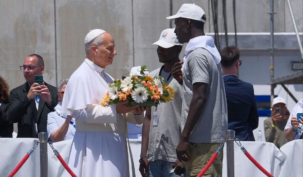 El Papa León XIV recibe flores de dos voluntarios para protagonizar una ofrenda floral en el mar.