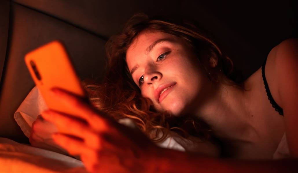 Foto de recurso de una joven mirando el móvil de noche