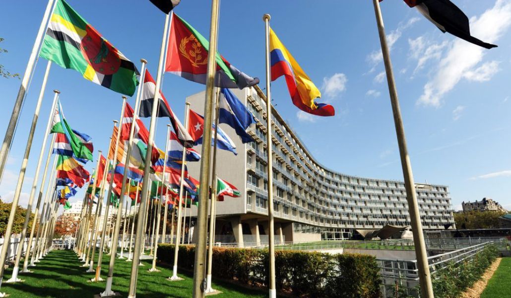 Fachada exterior de la sede de la UNESCO en París con banderas.